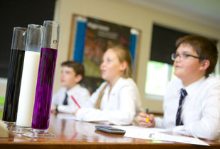 Kimbolton School Chemistry Lesson Featuring Test Tubes Filled with Liquids in the School Colours of Purple, Black and White